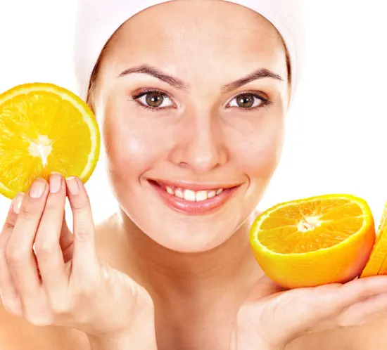 Woman holding orange slices to represent alpha hydroxy acid (AHA) peels and citrus-derived exfoliants.