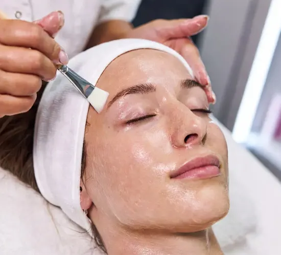 Woman receiving a light superficial facial peel treatment in a medical spa setting.
