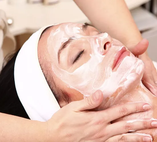 Woman receiving a facial treatment with cream applied to her face.
