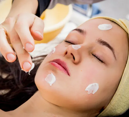 Woman receiving an acne-focused facial peel treatment with topical solution applied to active breakout-prone skin.